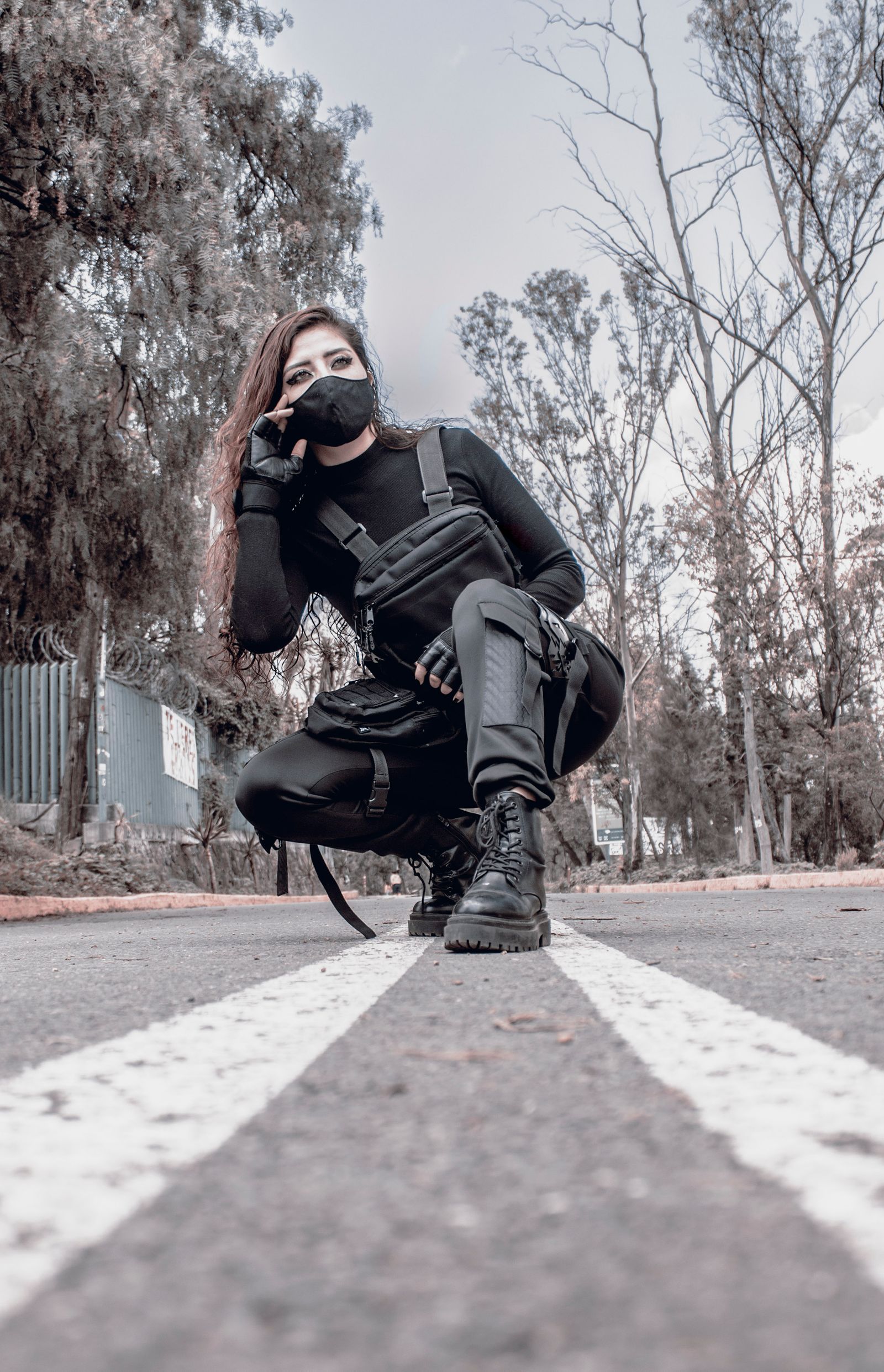 Woman in techwear crouching in the middle of the street